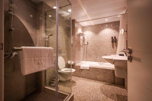 a bathroom with a shower and a toilet and a sink at Eko Hotel Suites in Lagos