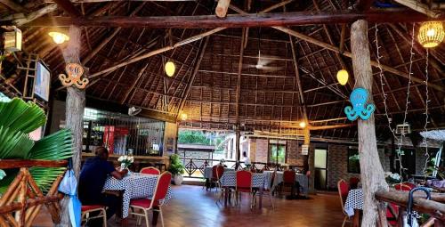 une personne assise à une table dans un restaurant dans l'établissement splash resort hotel, à Mtwara