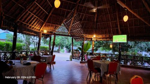 een restaurant met tafels en stoelen en een scherm bij splash resort hotel in Mtwara