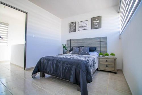 - une chambre avec un grand lit et une table de chevet avec un couvre-lit dans l'établissement Acogedora casa llena de vida, à San Luis Potosí