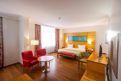 une chambre d'hôtel avec un lit et des chaises rouges dans l'établissement Eko Hotel Suites, à Lagos