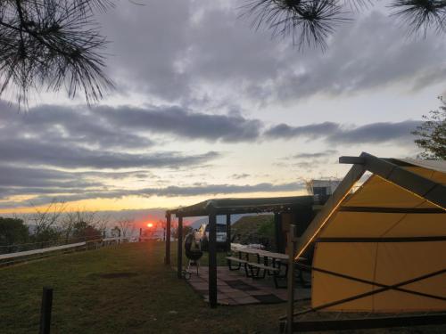 eine Bushaltestelle mit Bänken und Sonnenuntergang im Hintergrund in der Unterkunft 螢營的天空 免搭帳包區露營 in Li-chuang