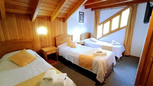 a hotel room with two beds and a window at Apart Hotel del Pellin in San Martín de los Andes