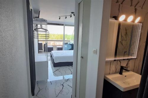 une chambre avec un lit et une salle de bain avec un lavabo dans l'établissement Studio 43, Héliopolis L au village naturiste, au Cap d'Agde