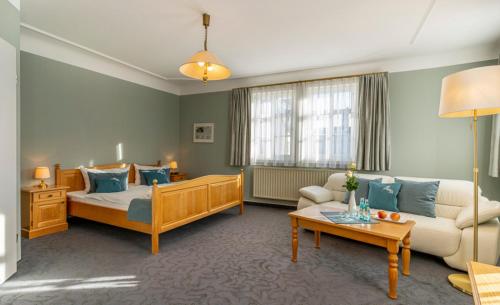 ein Wohnzimmer mit einem Bett und einem Sofa in der Unterkunft Hotel Roß in Zwönitz