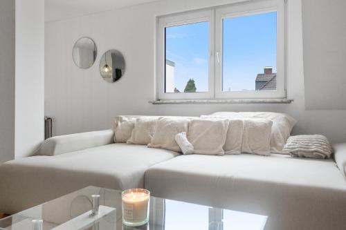 a white living room with a couch and a window at Skyview Retreat Maisonette in Essen