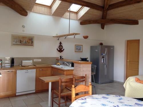 - une cuisine avec des placards en bois, une table et un réfrigérateur dans l'établissement Maison cosy entre vignes et plage, à Dolus-d'Oléron