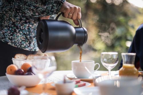 a woman pouring coffee into a cup on a table at Les Filolies in Saint-André-dʼAllas