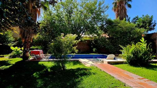 un patio con una piscina con 2 sillas y árboles en Casa del Buen Viaje en Mendoza