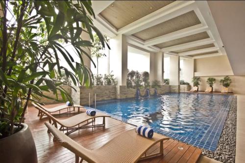 a swimming pool in a hotel with chairs and plants at KL Tower Condo, Makati City in Manila