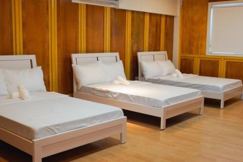 two beds in a room with wooden walls at Makati Altean Apartment (Delfin Room) in Manila