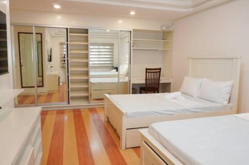 ein Schlafzimmer mit 2 Betten und ein Zimmer mit einem Schreibtisch in der Unterkunft Makati Altean Apartment (Leonora Room) in Manila