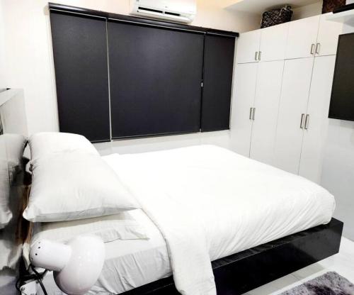 a bedroom with a white bed and black cabinets at Alpha Grandview Malate Condo 2005 in Manila