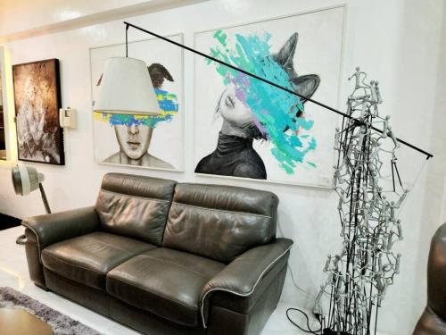 a living room with a leather couch and some pictures at Alpha Grandview Malate Condo 2005 in Manila