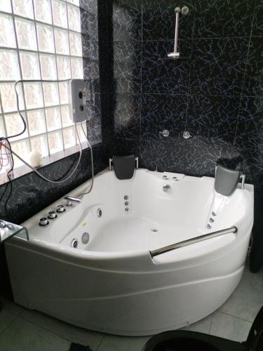 La salle de bains est pourvue d'une baignoire blanche et d'une fenêtre. dans l'établissement Habitación con jacuzzi y amoblado, à Huancayo