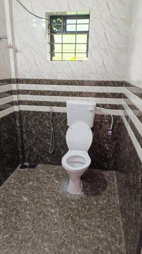 a bathroom with a white toilet in a room at Makayla Farm Stay in Pernem