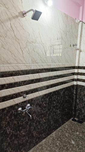 La salle de bains est pourvue d'une douche et d'un mur en marbre. dans l'établissement Makayla Farm Stay, à Pernem