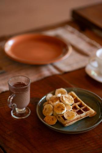 a plate of waffles and a glass of coffee on a table at Ecovila Coração da Mata in Brumadinho