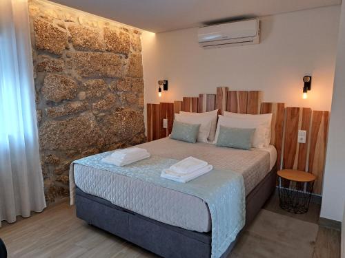 a bedroom with a bed in front of a stone wall at Agrafonte in Paços de Ferreira