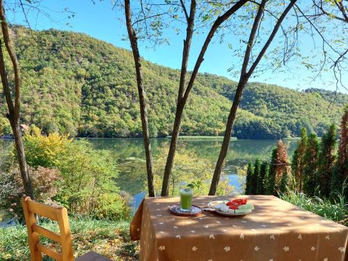 a table with a drink and fruit on it next to a lake at "Kod dva kestena"Warm and cozy house with lake view sauna in Međuvršje