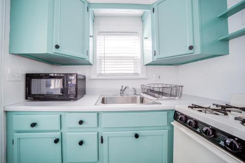 a kitchen with blue cabinets and a sink and a microwave at Waterfront Chautauqua Lake Home with Stunning Views in Jamestown