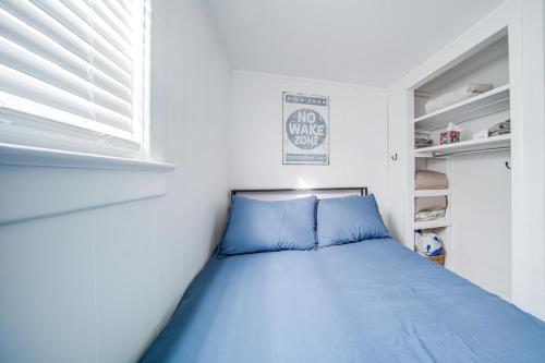 a small bedroom with a blue bed and a window at Jamestown Lake House with Boat Dock Access and Views! in Jamestown