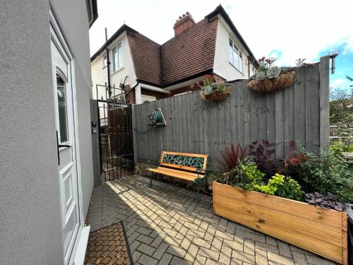 a backyard with a wooden bench in front of a fence at Cosy Studio Flat in Hither Green