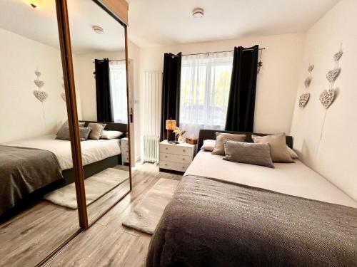 a bedroom with two beds and a mirror at Cosy Studio Flat in Hither Green