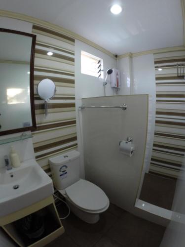 a bathroom with a white toilet and a sink at Coron Residencia de Rosario in Coron