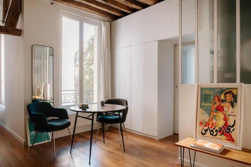 a dining room with a table and chairs and a window at Charming Paris Hideaway in Paris