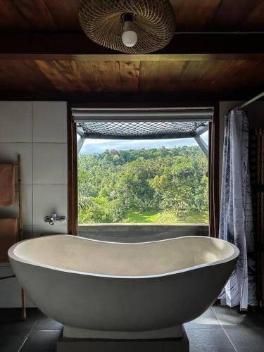 eine Badewanne im Bad mit Fenster in der Unterkunft Karyasari kabin - Tiny House in Blimbing