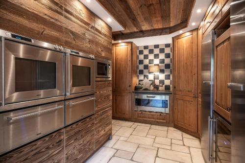a kitchen with wooden walls and stainless steel appliances at Chalet Ruitor, chalet 500 m2 luxueux de caractère in Sainte-Foy-Tarentaise