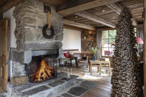 a stone fireplace in a living room with a table and chairs at Chalet Ruitor, chalet 500 m2 luxueux de caractère in Sainte-Foy-Tarentaise