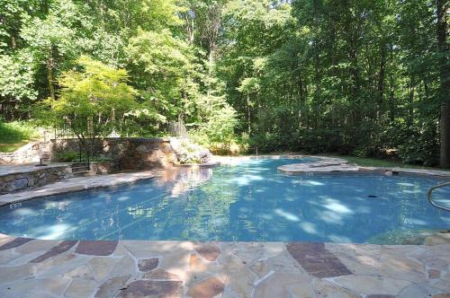a large pool with blue water in a yard at Serendipity -- Hot Tub - Pet Friendly - Fire Pit - Grill - Porch - Deck - Wifi - Pool Access - Games in Berkeley Springs