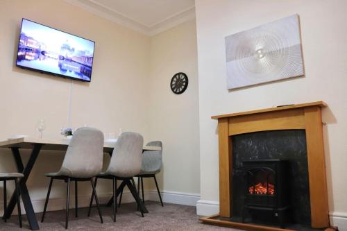 a living room with a table and a fireplace at Comfortable 2 Bedroom House in Beeston Hill