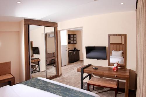 Un dormitorio con una cama, un escritorio y un televisor. en POST Hotel Amman, en Amán