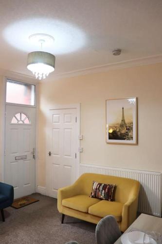 a living room with a yellow chair and a window at Comfortable 2 Bedroom House in Beeston Hill
