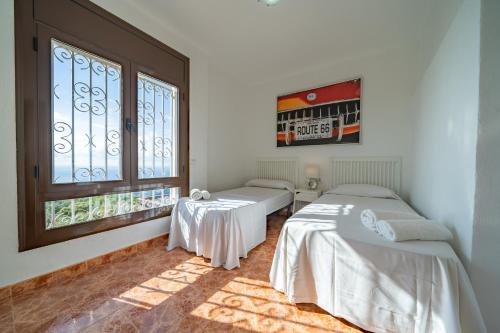 2 camas en una habitación con ventana en HomeHolidaysRentals Malvina, en Pineda de Mar