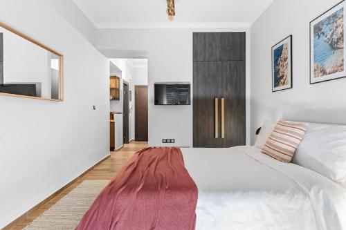 a bedroom with a white bed with a red blanket on it at On The Port: Studio in Rafina