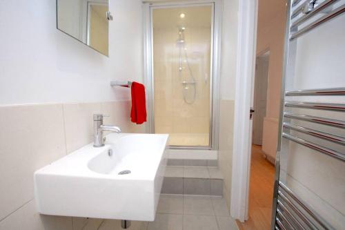 a white bathroom with a sink and a shower at Lovely South Kensington Flat in London
