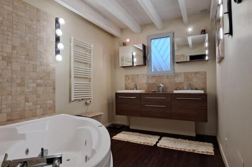 baño con bañera, 2 lavabos y ventana en Villa Cara avec piscine privée, en Carpentras