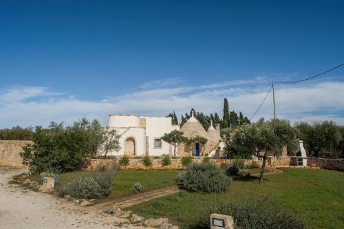 a large white house with trees and a yard at TrullOlive in Ostuni