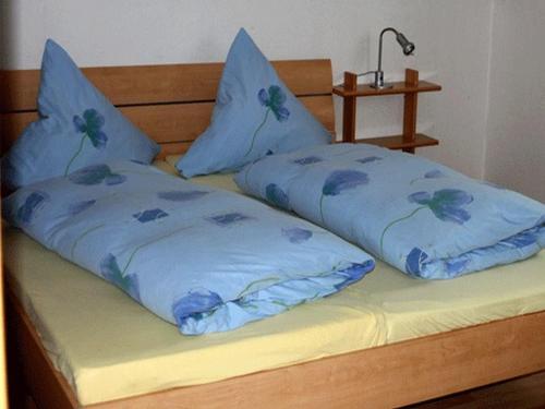 ein Bett mit blauer Bettwäsche und Kissen darauf in der Unterkunft Haus Eichhölzle in Bichishausen
