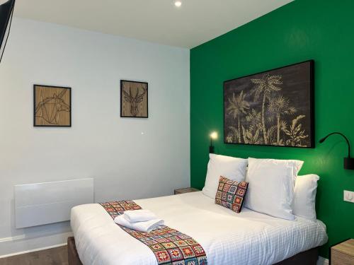 ヴィシーにあるLogis Hôtel Belle Etoile Vichyの緑色のアクセントの壁とベッドが備わるベッドルーム1室