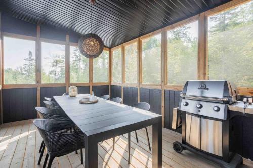 cocina con mesa y fogones y algunas ventanas en Chalet Reine des Pres, en Saint-Gabriel-de-Brandon