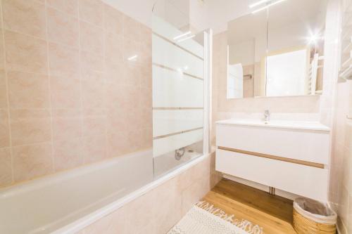 une salle de bain avec une baignoire, un lavabo et un miroir dans l'établissement Picasso & Terrasse - 2 Chambres, à Brive-la-Gaillarde