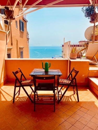 una mesa y sillas en un balcón con vistas al océano en La casetta en Nápoles