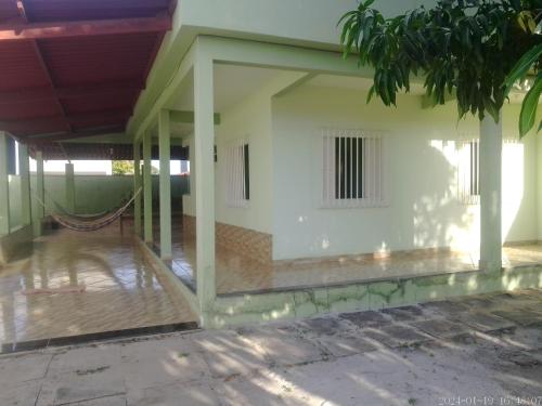 a building with a white wall and a porch at Casa praia de Guriri temporada in Guriri