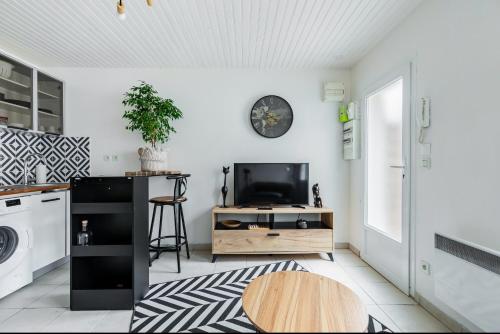 a kitchen with a table and a tv on a wall at Maisonnette Jardin Merignac in Mérignac