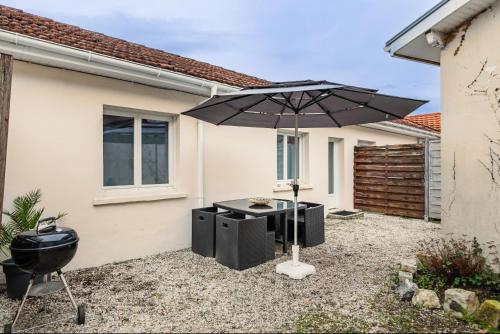 a grill and an umbrella in front of a house at Maisonnette Jardin Merignac in Mérignac